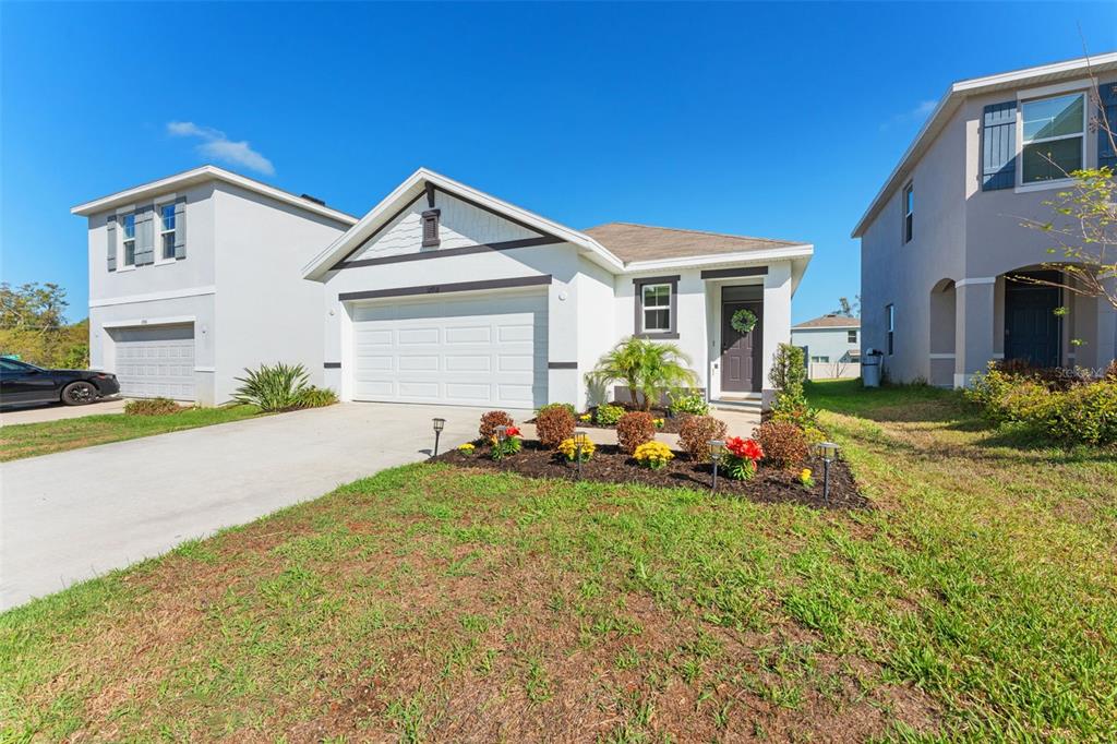 A single-story house with a white exterior, a two-car garage, and a landscaped front garden — 10918 TRAILING VINE DRIVE, TAMPA, FL