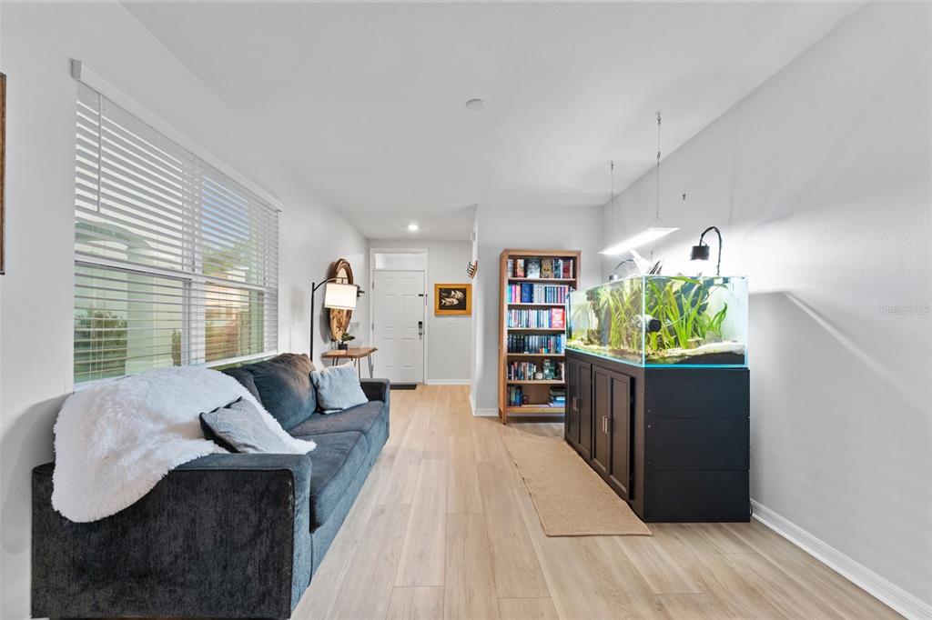 A living room features a dark sofa, a large aquarium on a black stand, and bookshelves — 10918 TRAILING VINE DRIVE, TAMPA, FL