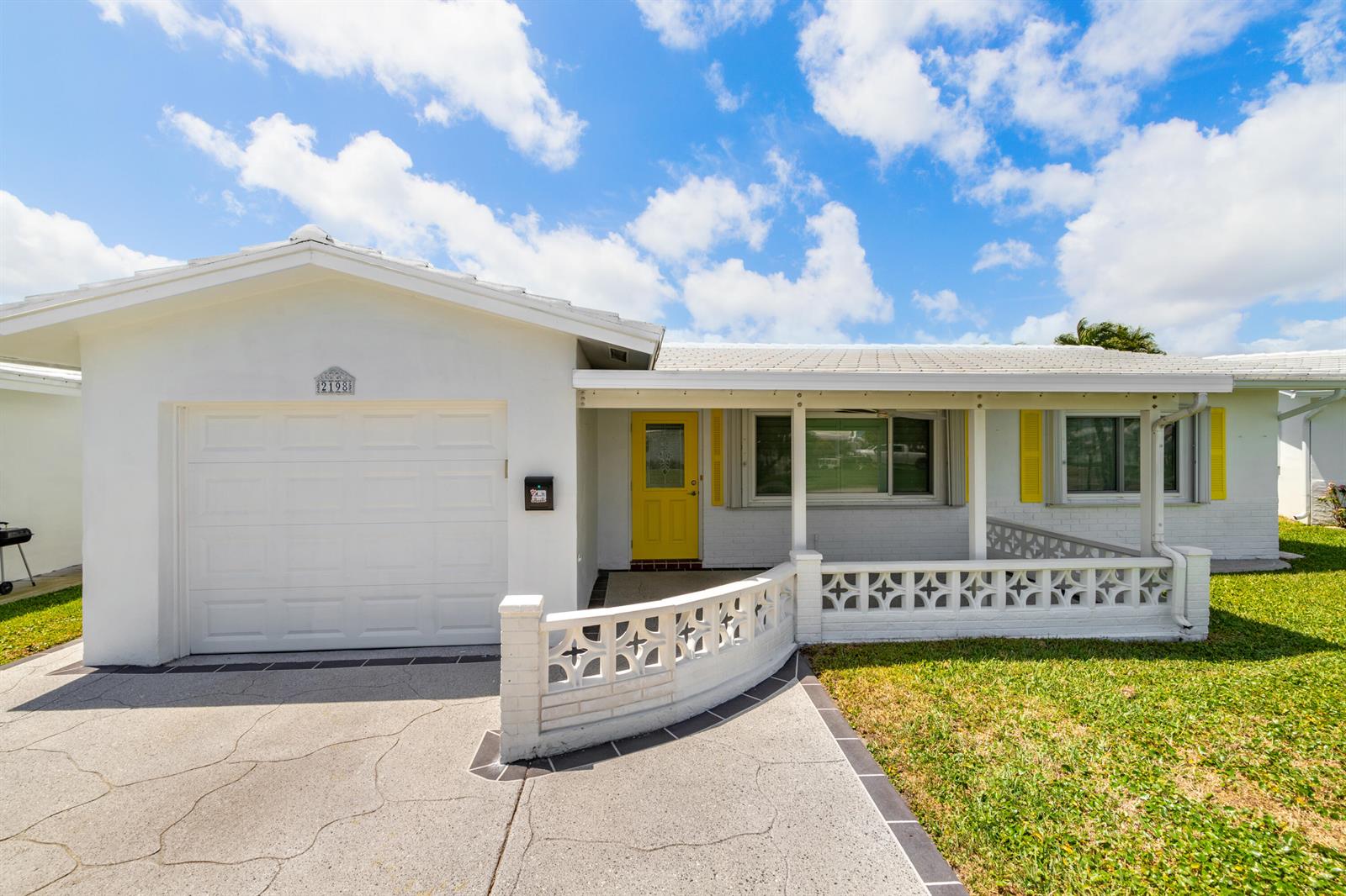 A white single-story house features a yellow front door, a garage, and decorative concrete blocks — 2198 SW 12th Avenue, Boynton Beach FL 33426, BOYNTON BEACH, FL
