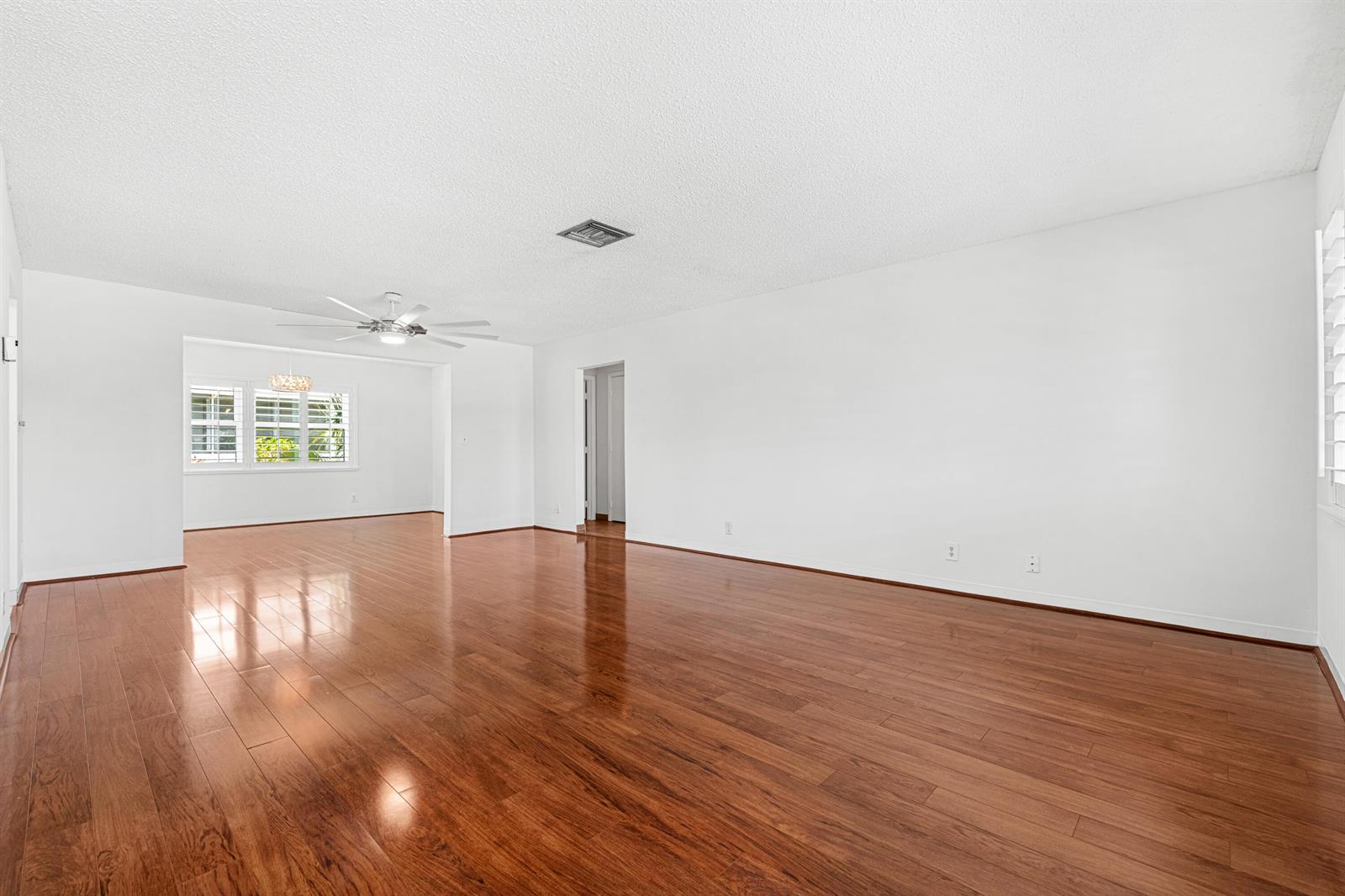 An empty living room features white walls, a ceiling fan, and polished hardwood flooring — 2198 SW 12th Avenue, Boynton Beach FL 33426, BOYNTON BEACH, FL