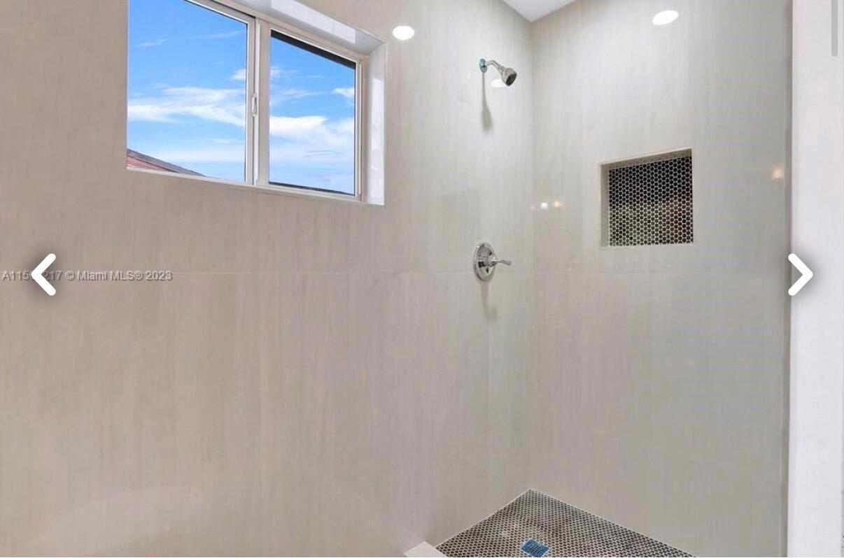 A walk-in shower features light-colored wall tiles, a mosaic-tiled floor, and a small window — 6720 Coolidge Street, Hollywood FL 33024, HOLLYWOOD, FL