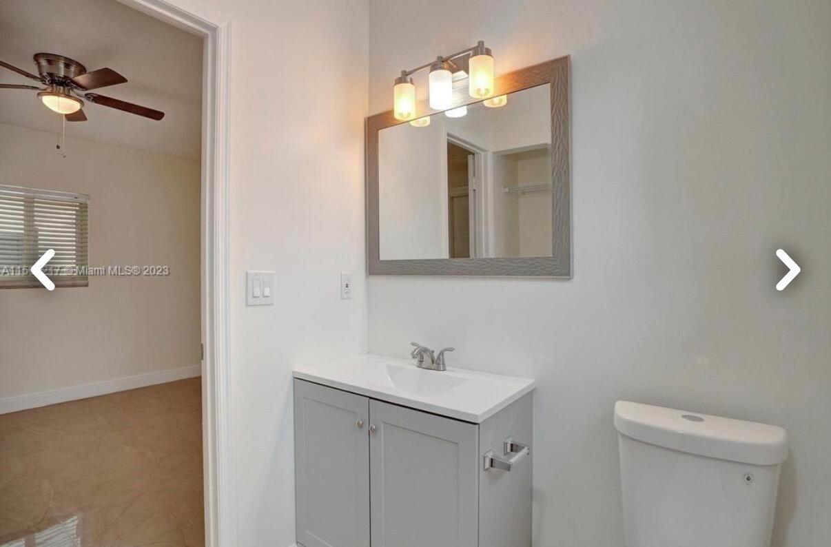A bathroom features a gray vanity with a white countertop, a mirror, and a toilet — 6720 Coolidge Street, Hollywood FL 33024, HOLLYWOOD, FL