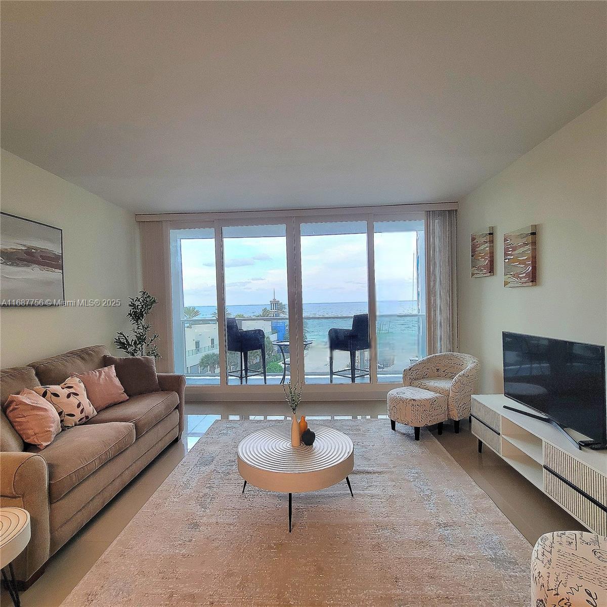 A living room features a beige sofa, circular coffee table, and floor-to-ceiling windows overlooking the ocean — 3505 S Ocean Dr # 507, Hollywood FL 33019, HOLLYWOOD, FL