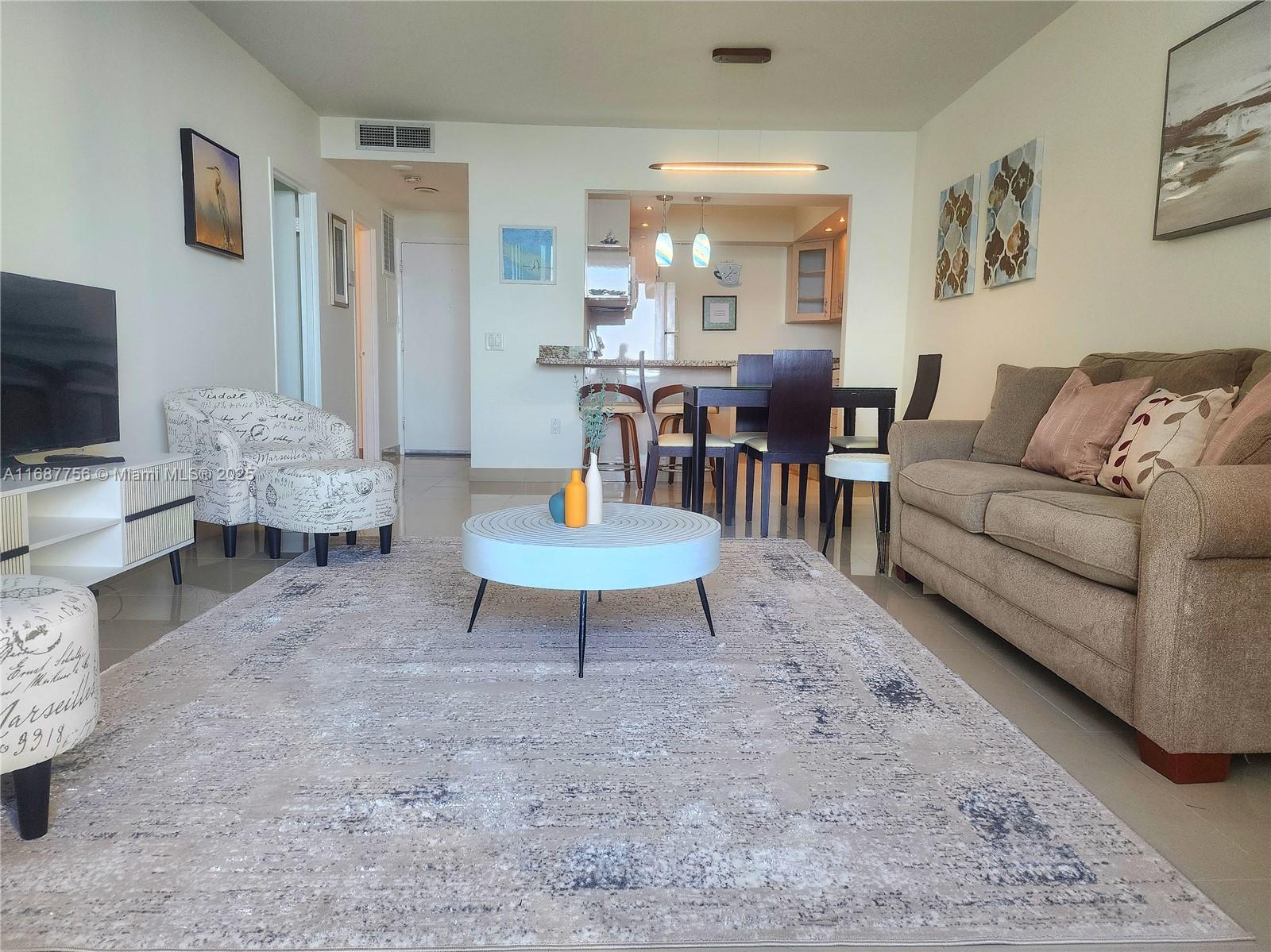A living room features a beige sofa, a patterned armchair, and a circular coffee table — 3505 S Ocean Dr # 507, Hollywood FL 33019, HOLLYWOOD, FL