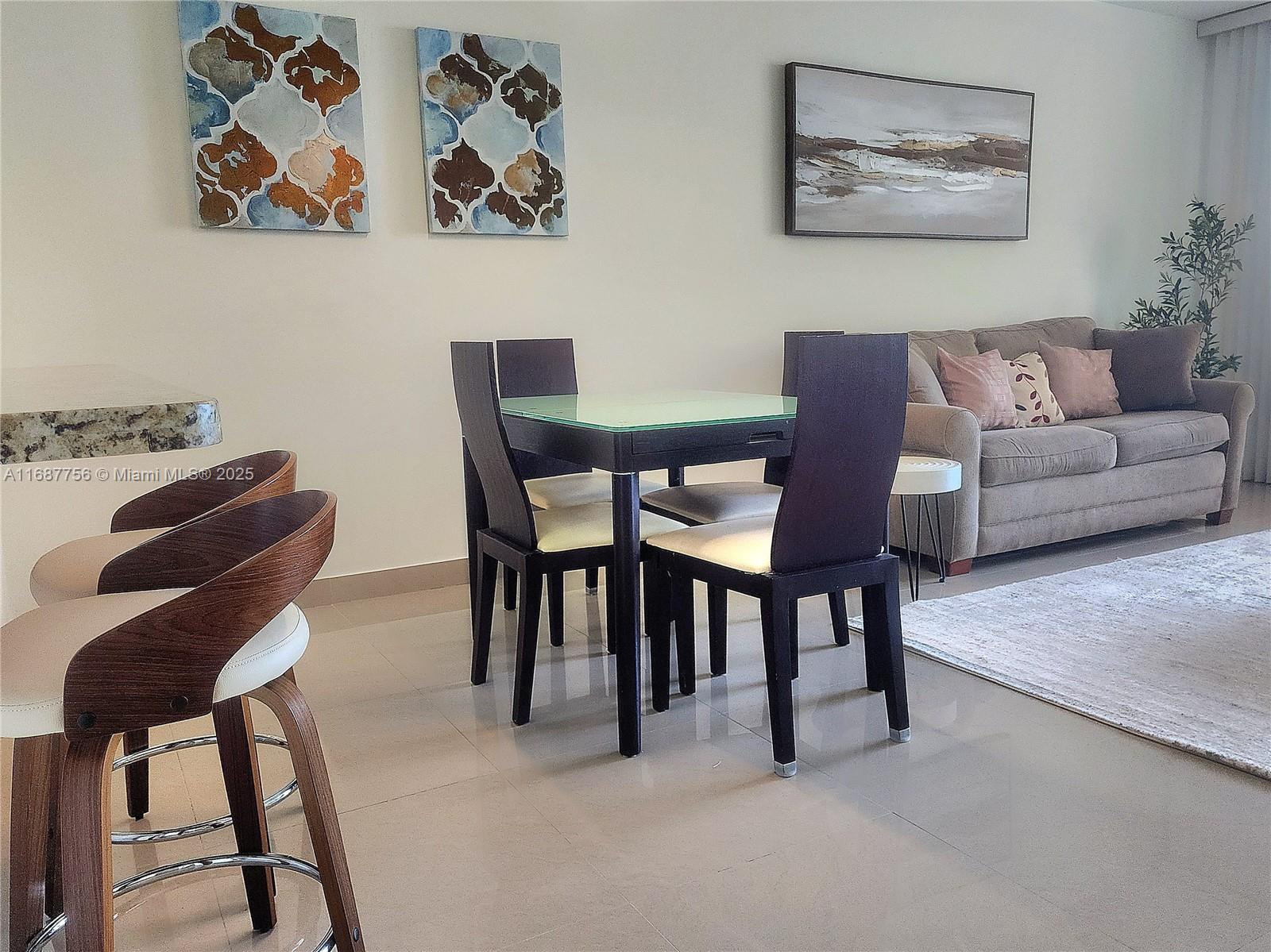 A dining area with a glass-topped table and chairs sits beside a living room sofa — 3505 S Ocean Dr # 507, Hollywood FL 33019, HOLLYWOOD, FL