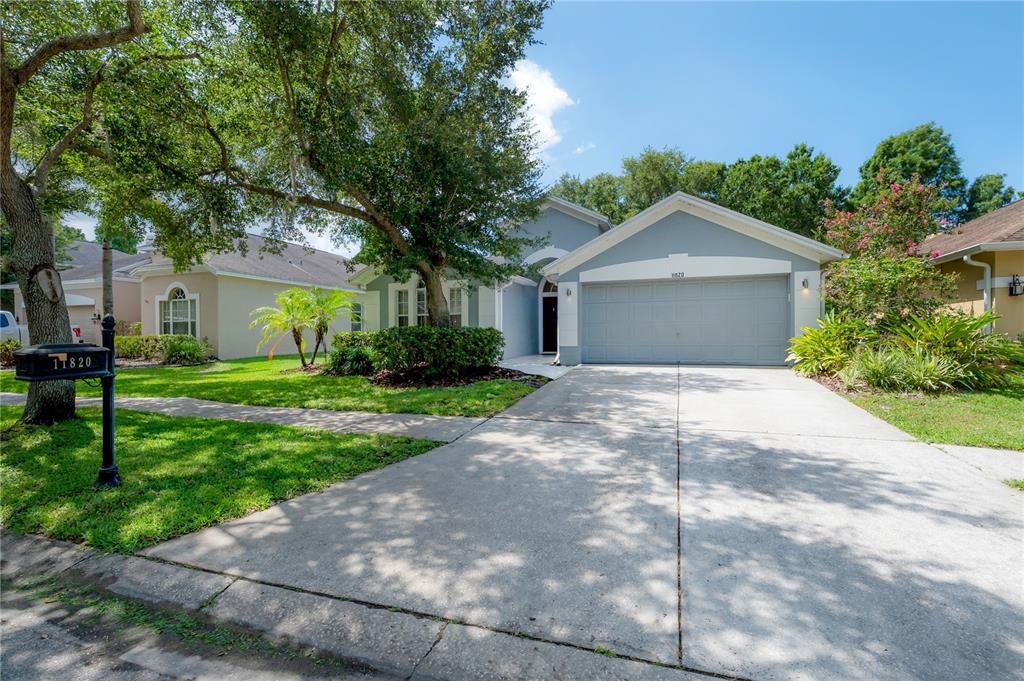 A single-story house with a gray exterior, two-car garage, and a large front yard — 11820 EASTHAMPTON DRIVE, TAMPA, FL
