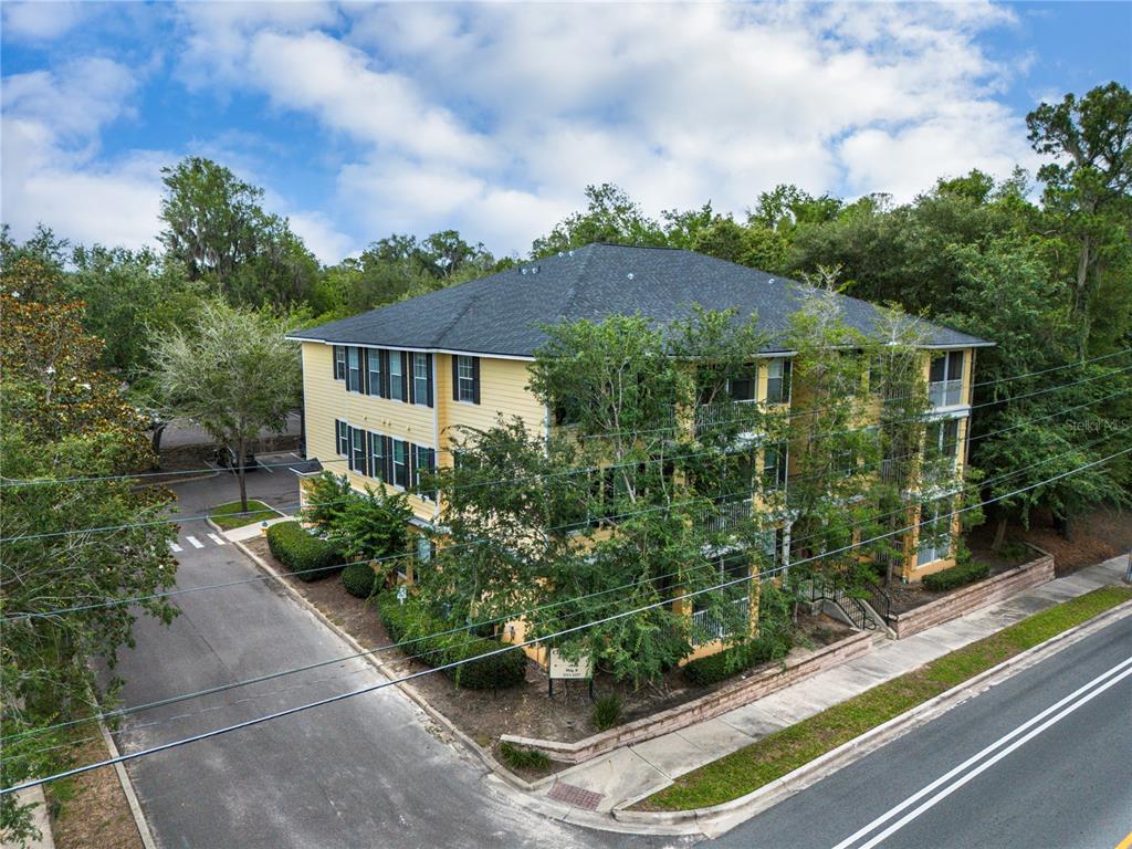 An aerial view shows a multi-story apartment building surrounded by trees near a road — 2227 NW 16TH TERRACE, GAINESVILLE, FL