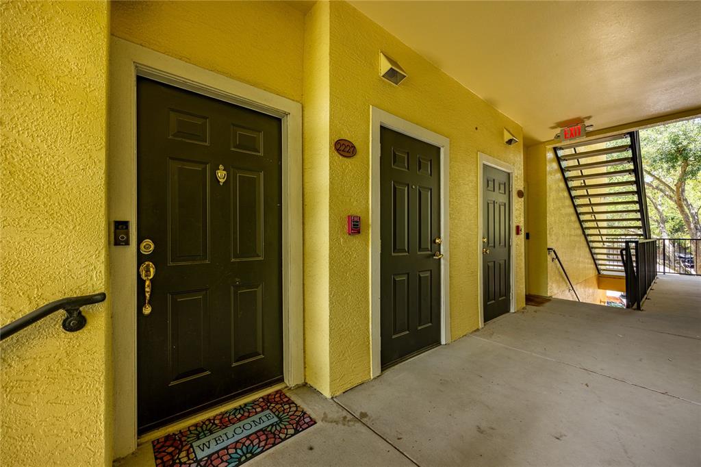 An exterior view of a three-story yellow apartment building with a dark shingled roof — 2227 NW 16TH TERRACE, GAINESVILLE, FL