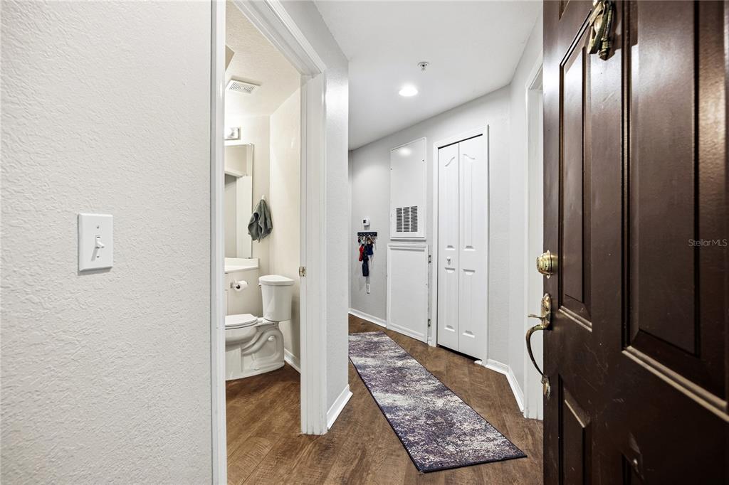 An exterior view of a yellow apartment building hallway with three dark doors and stairs — 2227 NW 16TH TERRACE, GAINESVILLE, FL