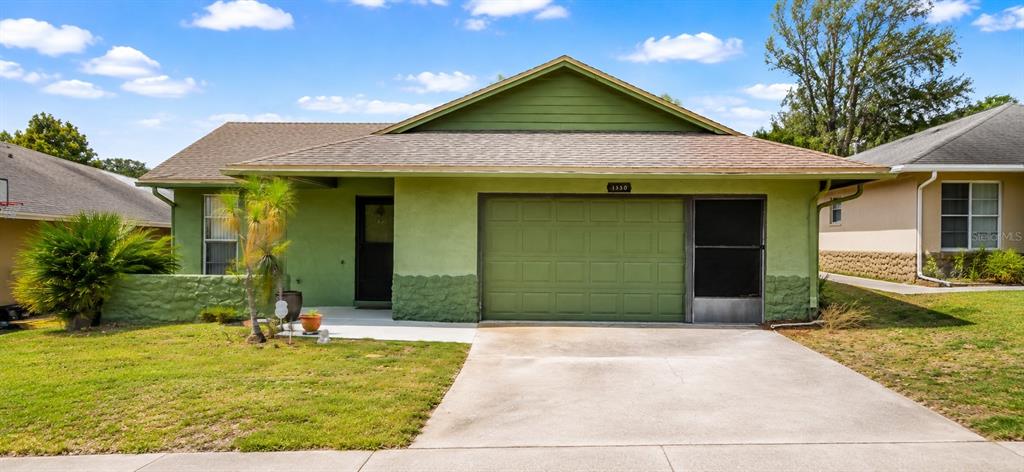 A single-story green house with a concrete driveway, a garage, and a small front yard — 1350 PALO ALTO COURT, WINTER SPRINGS, FL