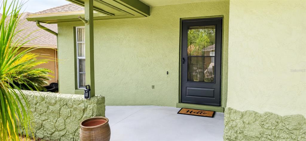 A light green house exterior features a covered porch, a black storm door, and stone accents — 1350 PALO ALTO COURT, WINTER SPRINGS, FL