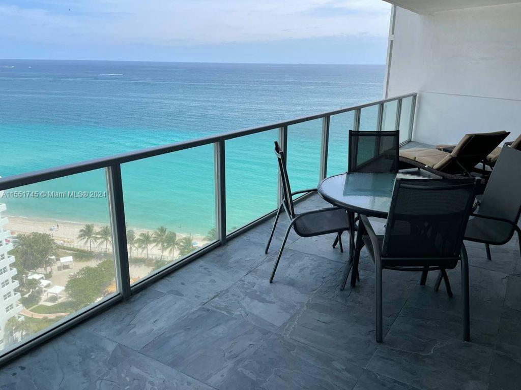 A balcony with a glass railing, patio furniture, and a view of the ocean — 3101 S OCEAN DR # 2003, Hollywood FL 33019, HOLLYWOOD, FL