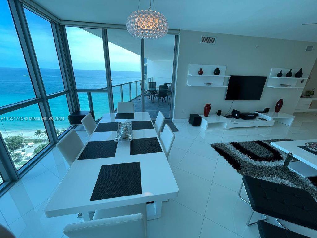 A dining area with a white table and chairs overlooks the ocean through floor-to-ceiling windows — 3101 S OCEAN DR # 2003, Hollywood FL 33019, HOLLYWOOD, FL