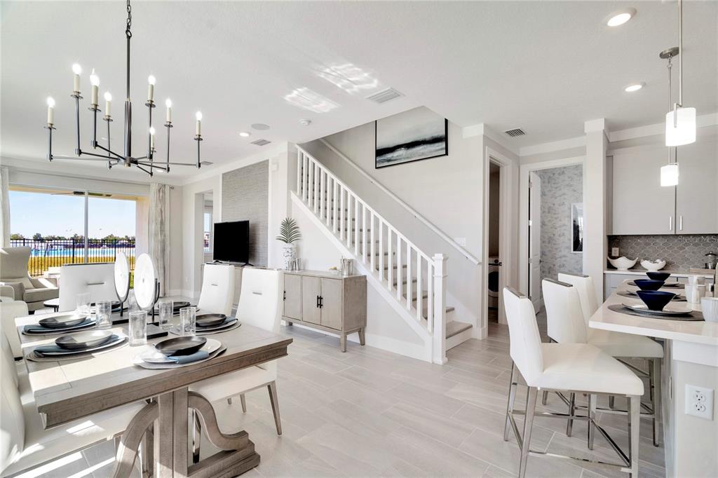 An open-concept dining and kitchen area features a staircase, light wood flooring, and modern decor — 32119 ANCHOR POINT DRIVE, WESLEY CHAPEL, FL