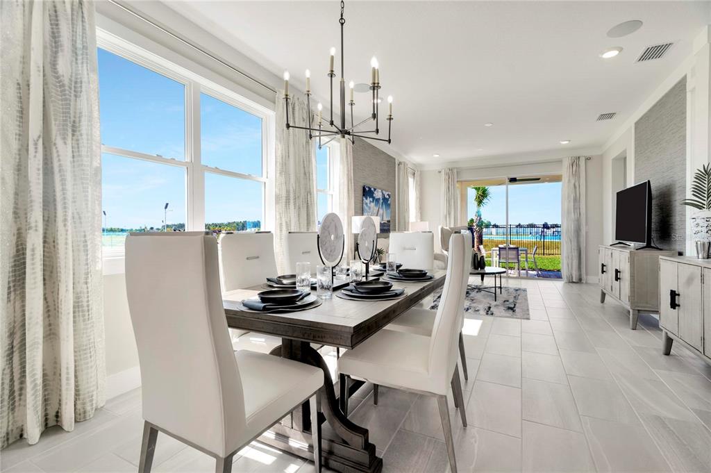 A dining room with a wooden table, white chairs, and a view of a pool — 32119 ANCHOR POINT DRIVE, WESLEY CHAPEL, FL