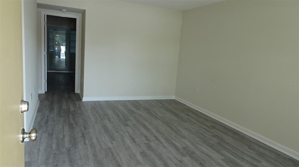 A living room features light wood-look flooring, a wall-mounted television, and a colorful abstract painting — 8100 DR MARTIN LUTHER KING JR STREET N UNIT 105, ST PETERSBURG, FL