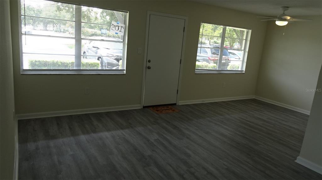 An empty room with light-colored walls and gray wood-look flooring leads to a doorway — 8100 DR MARTIN LUTHER KING JR STREET N UNIT 105, ST PETERSBURG, FL