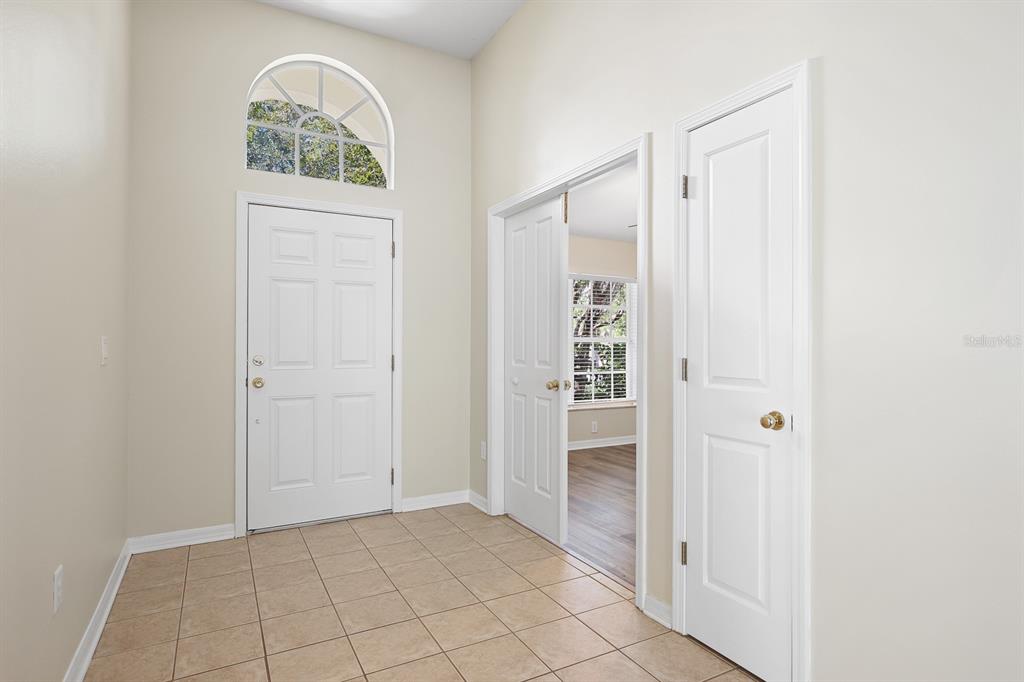 An entryway with tile flooring, a white front door, and a doorway leading to another room — 6328 BRIDGECREST DRIVE, LITHIA, FL