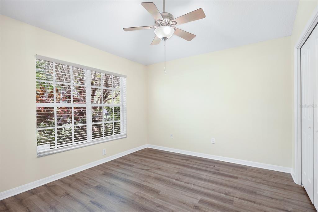 An empty bedroom features light-colored walls, wood-look flooring, a ceiling fan, and a large window — 6328 BRIDGECREST DRIVE, LITHIA, FL