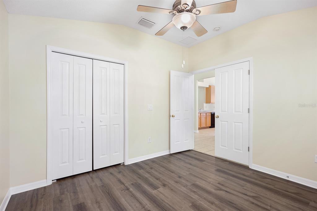 A bedroom with light-colored walls, wood-look flooring, a ceiling fan, and white interior doors — 6328 BRIDGECREST DRIVE, LITHIA, FL