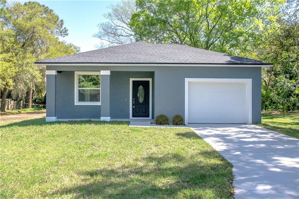 A single-story gray house with a white-trimmed window, front door, and attached garage — 1777 BURROWS LANE, SANFORD, FL
