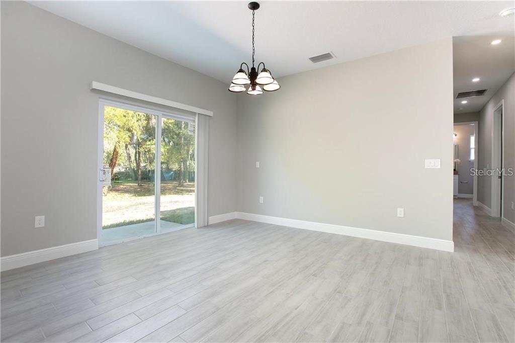 A dining area with light gray tile flooring, a chandelier, and a sliding glass door — 1777 BURROWS LANE, SANFORD, FL