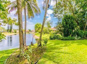 A grassy backyard with palm trees overlooks a small lake on a sunny day — 6310 NW 58th Way # 1, Parkland FL 33067, PARKLAND, FL
