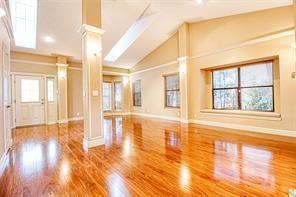 A bright, empty room features polished hardwood floors, vaulted ceilings, and large windows — 6310 NW 58th Way # 1, Parkland FL 33067, PARKLAND, FL
