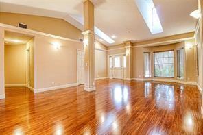 An empty room with hardwood floors, a vaulted ceiling, skylights, and a central support column — 6310 NW 58th Way # 1, Parkland FL 33067, PARKLAND, FL