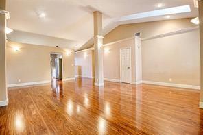 A spacious, empty room features polished hardwood floors, a central support column, and recessed lighting — 6310 NW 58th Way # 1, Parkland FL 33067, PARKLAND, FL