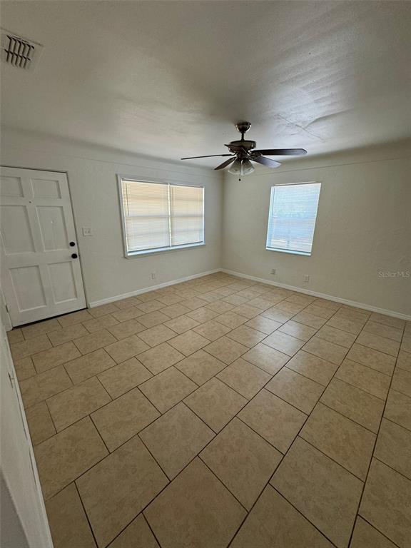 An empty room features beige tile flooring, a ceiling fan, and two windows — 2027 37TH STREET S, ST PETERSBURG, FL