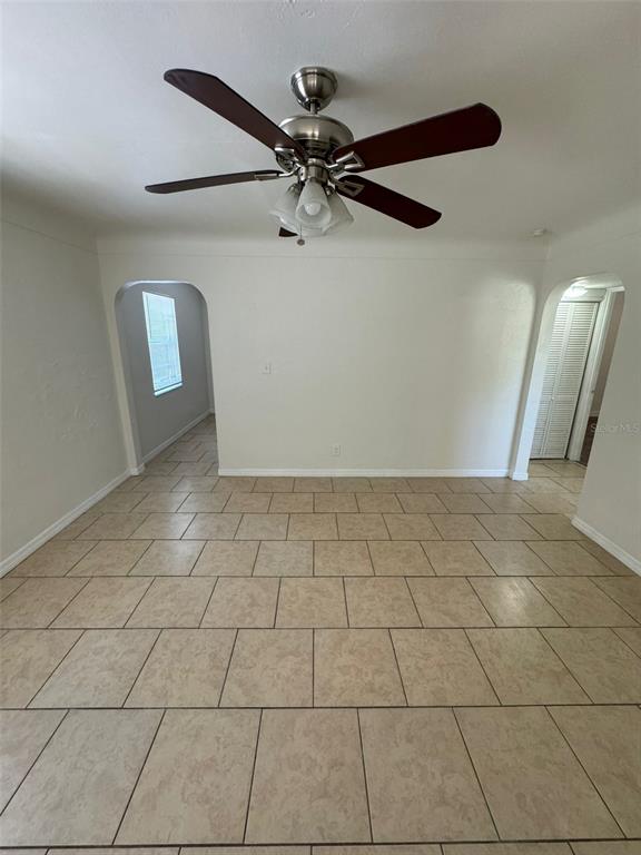 A room with light-colored tile flooring, a ceiling fan, and two arched doorways — 2027 37TH STREET S, ST PETERSBURG, FL