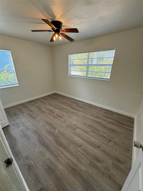 An empty bedroom features light-colored walls, wood-look flooring, and a ceiling fan with lights — 2027 37TH STREET S, ST PETERSBURG, FL