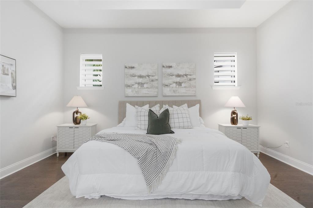 A bedroom features a king bed with white bedding, two nightstands, and two windows — 13856 ELIOT AVENUE, ORLANDO, FL
