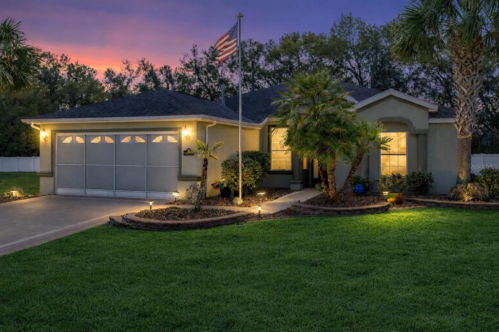 A single-story house with a garage, a flag pole, and landscaping at dusk — 16339 SW 14TH AVE ROAD, OCALA, FL