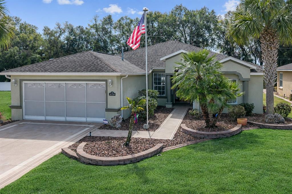 A single-story house with a screened garage door, a flag pole, and landscaped front yard — 16339 SW 14TH AVE ROAD, OCALA, FL