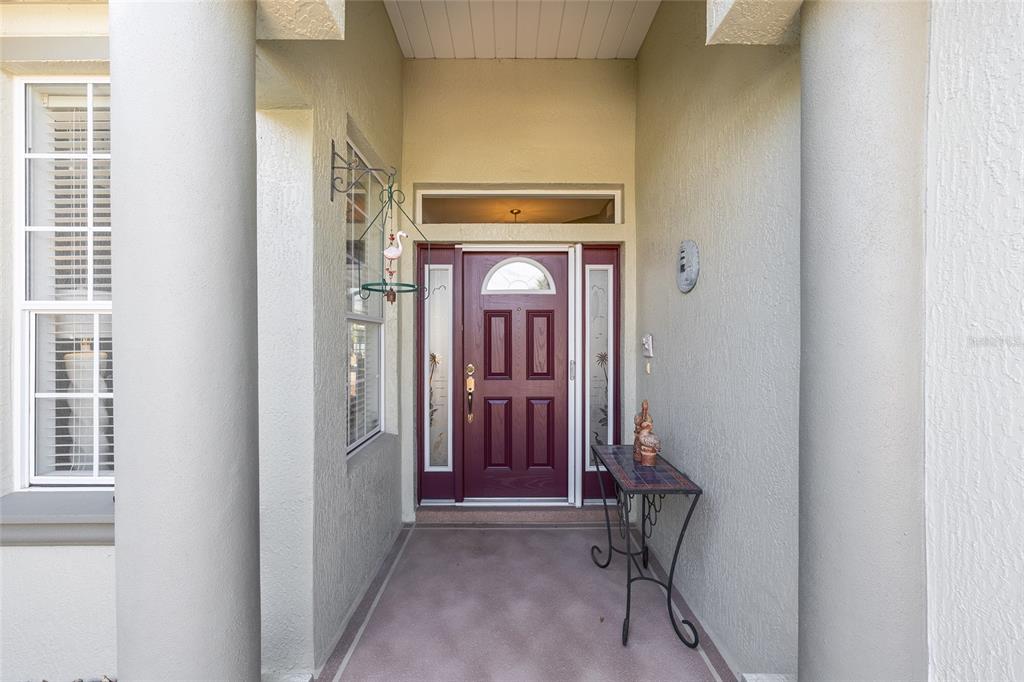 A covered entryway features a maroon front door with sidelights and a decorative metal table — 16339 SW 14TH AVE ROAD, OCALA, FL