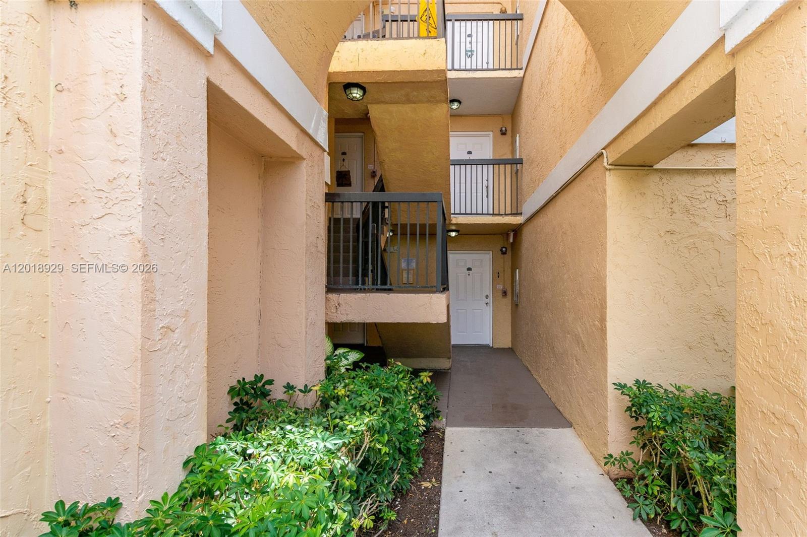 An exterior view of a multi-story apartment building with stairs and a concrete walkway — 5721 Riverside Dr, Coral Springs FL 33067, CORAL SPRINGS, FL