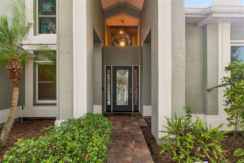 A front entryway features a brick walkway leading to a glass-paneled door under a high arch — 1128 MAINSAIL DRIVE, TARPON SPRINGS, FL