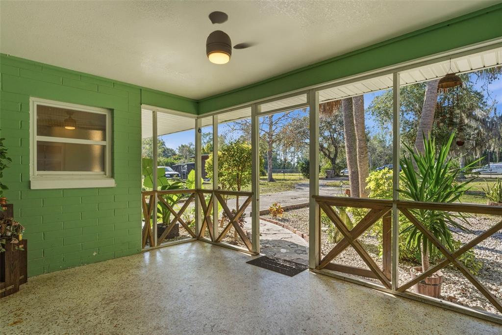 A screened-in porch with green painted brick walls, a speckled floor, and wooden railings — 26310 FISHERMANS ROAD, PAISLEY, FL