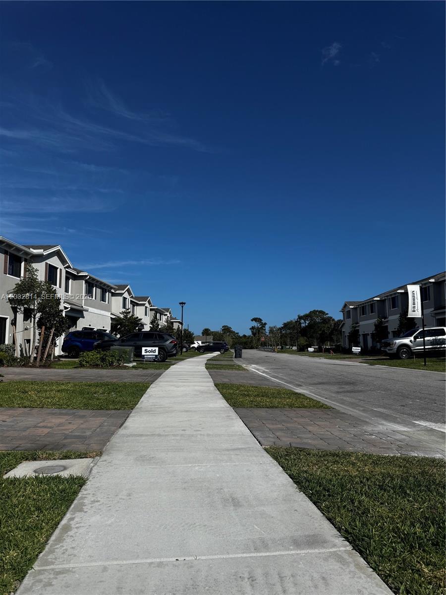 A sidewalk leads between two rows of modern townhouses under a clear blue sky — 4860 Dillion St # 4860, Lake Worth FL 33463, LAKE WORTH, FL