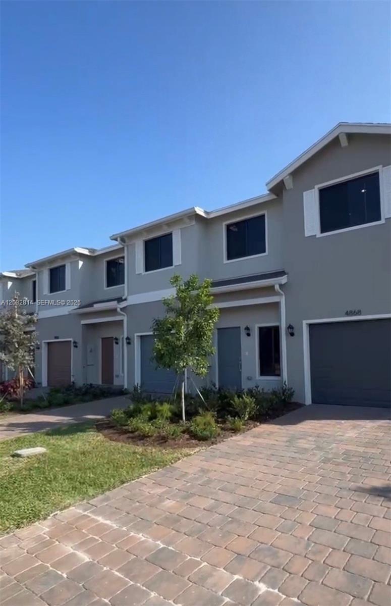 A row of two-story townhouses features gray stucco siding, dark-framed windows, and paved driveways — 4860 Dillion St # 4860, Lake Worth FL 33463, LAKE WORTH, FL