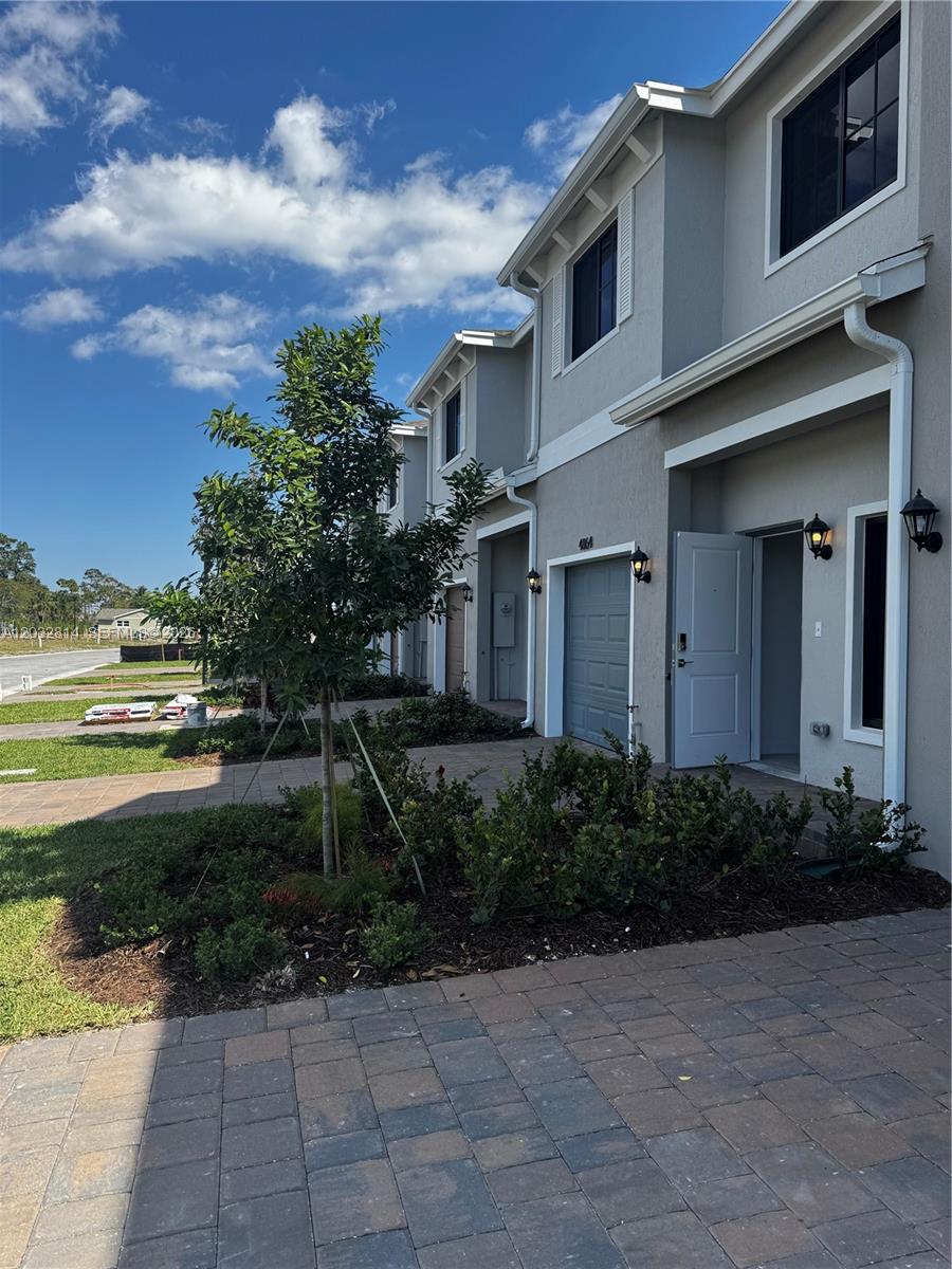 A row of modern two-story townhomes with gray stucco exteriors, paver driveways, and small front gardens — 4860 Dillion St # 4860, Lake Worth FL 33463, LAKE WORTH, FL