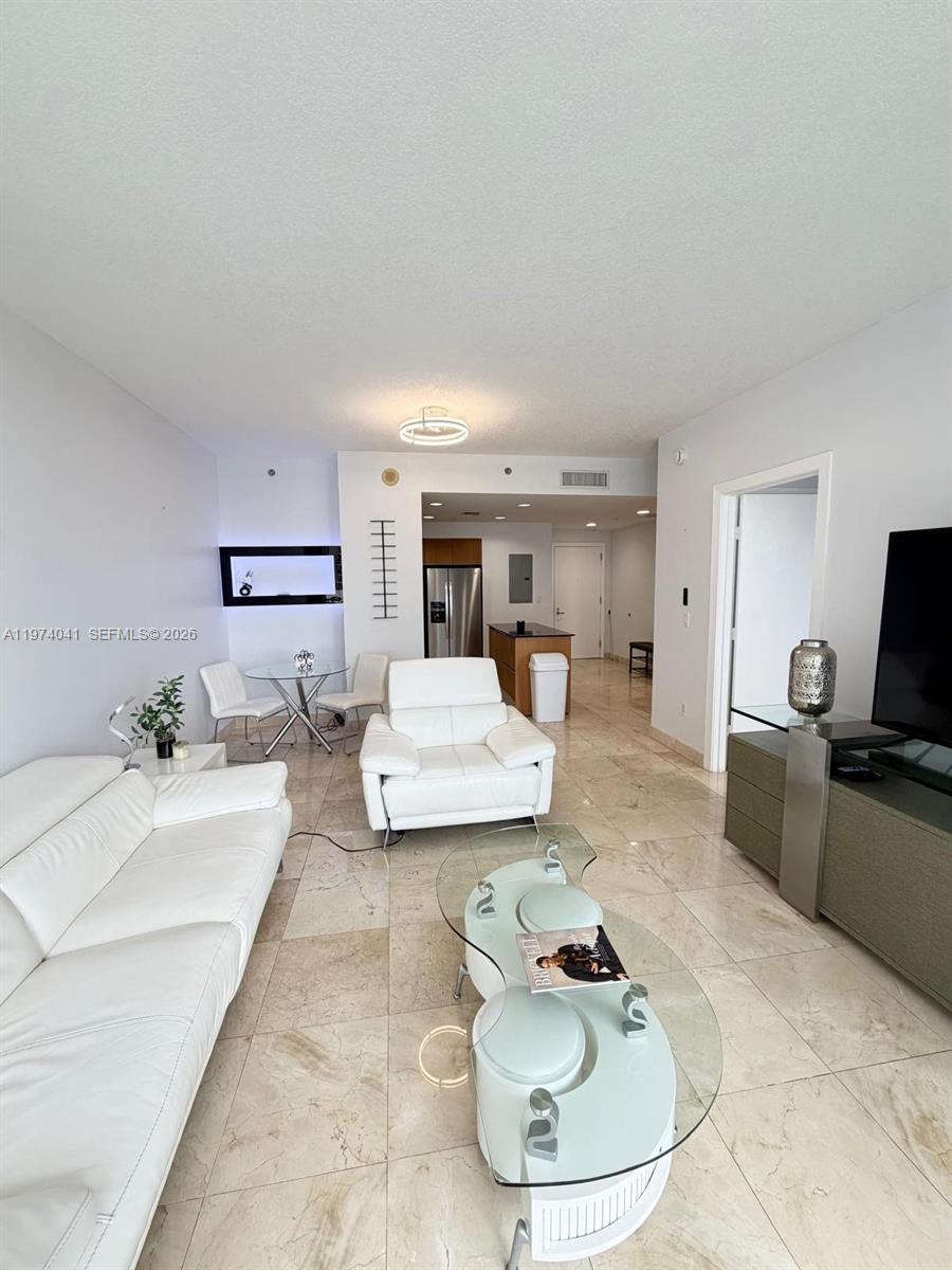 A living room features white leather furniture, a glass coffee table, and light tile flooring — 1050 Brickell Ave # 1904, Miami FL 33131, MIAMI, FL