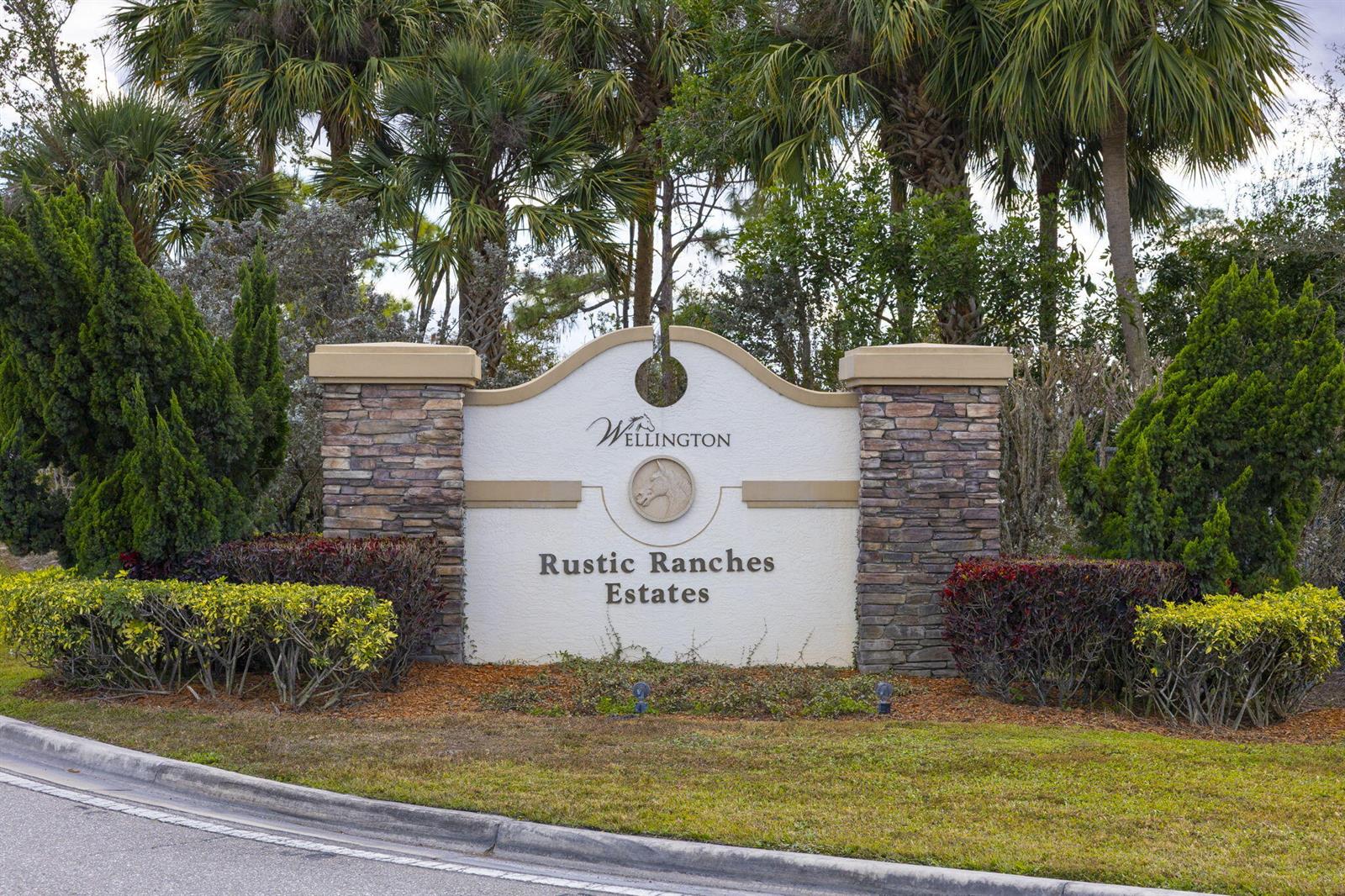 A stone and stucco monument sign for Rustic Ranches Estates stands before palm trees — 16296 Deer Path Lane, Wellington FL 33470, WELLINGTON, FL