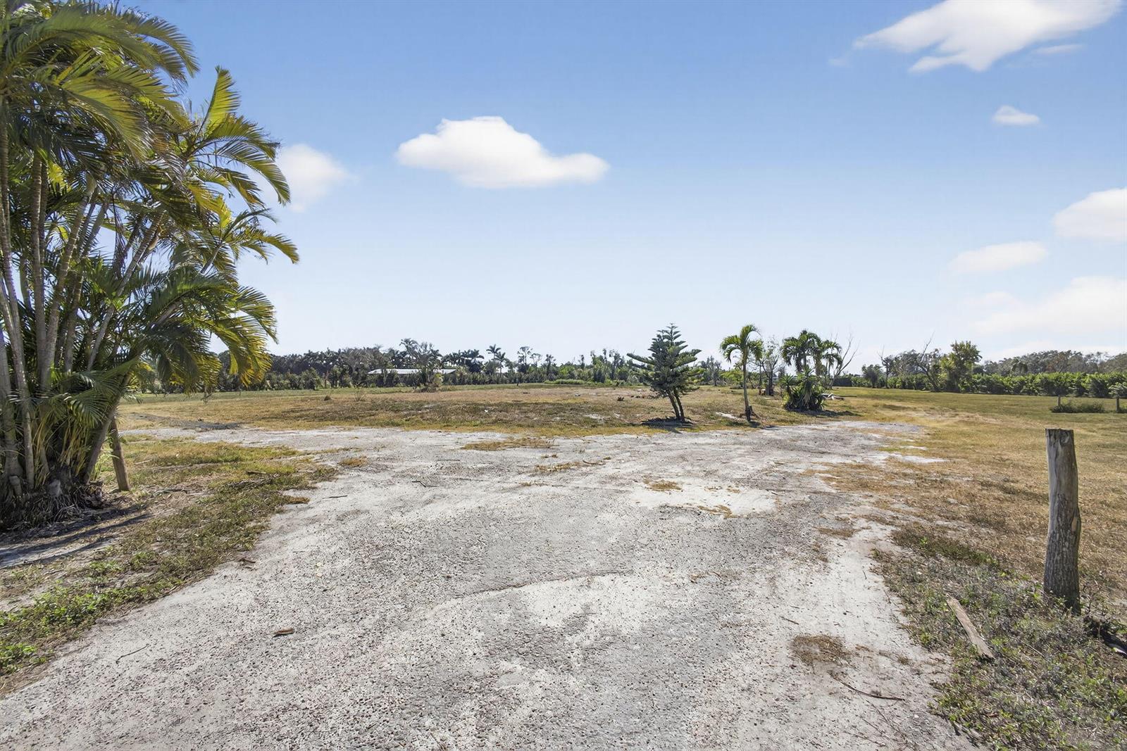 A wide, unpaved dirt driveway leads into a large, flat, grassy vacant lot — 16296 Deer Path Lane, Wellington FL 33470, WELLINGTON, FL