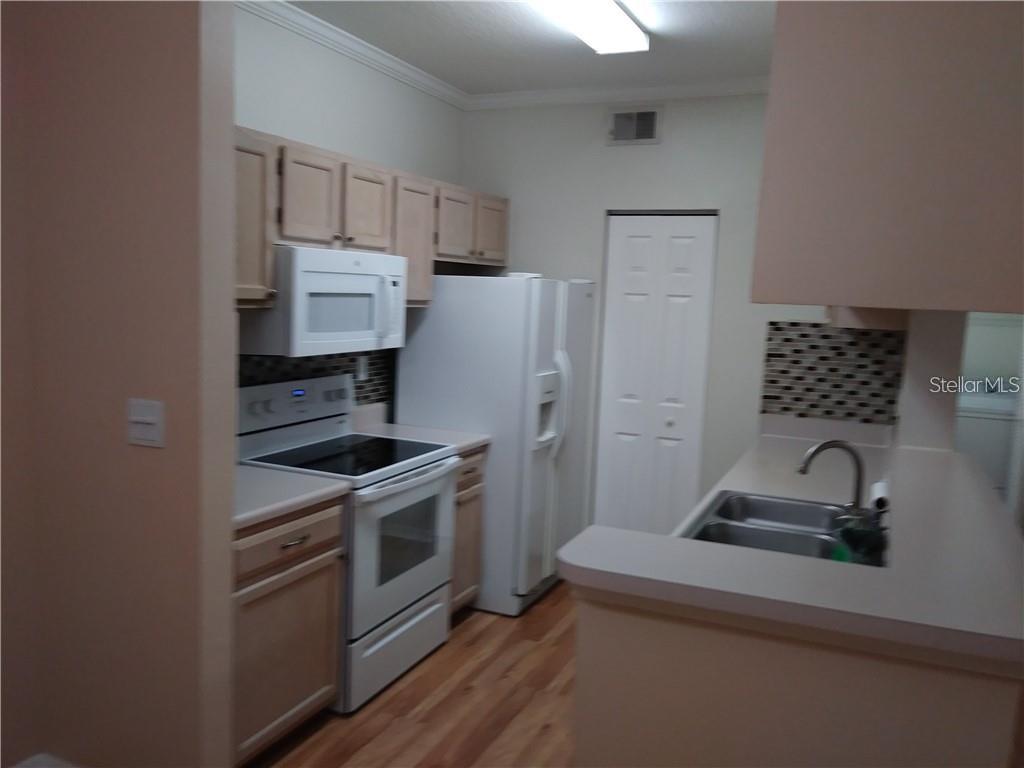 A kitchen features light wood cabinets, white appliances, a double sink, and wood-look flooring — 5620 PINNACLE HEIGHTS CIRCLE UNIT 305, TAMPA, FL