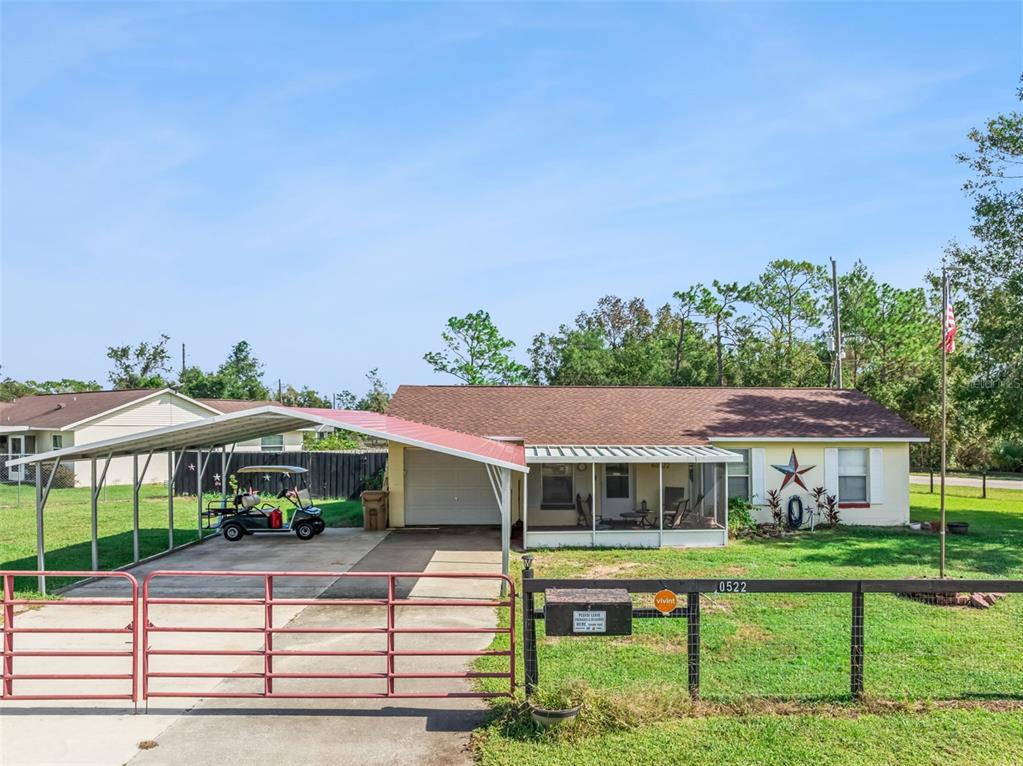 A single-story house with a carport, a screened porch, and a red metal gate — 40522 W 5TH AVENUE, UMATILLA, FL