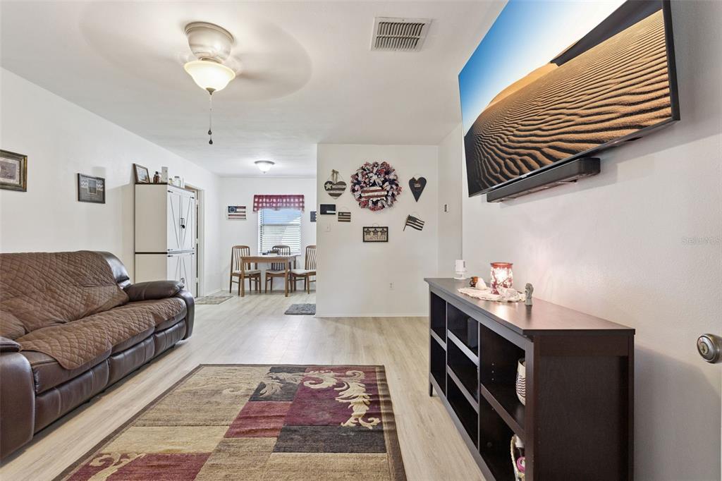 A living room features a brown leather sofa, a television, and a dining area beyond — 40522 W 5TH AVENUE, UMATILLA, FL