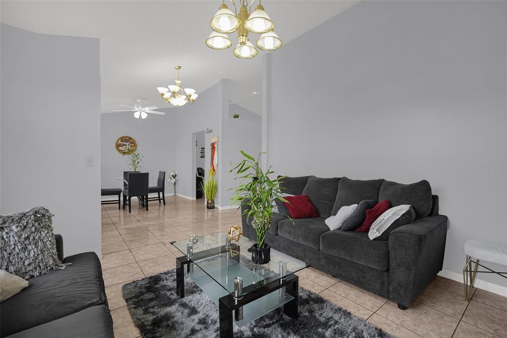 A living room with tile floors, a gray sofa, and a glass coffee table — 230 LYTTON CIRCLE, ORLANDO, FL